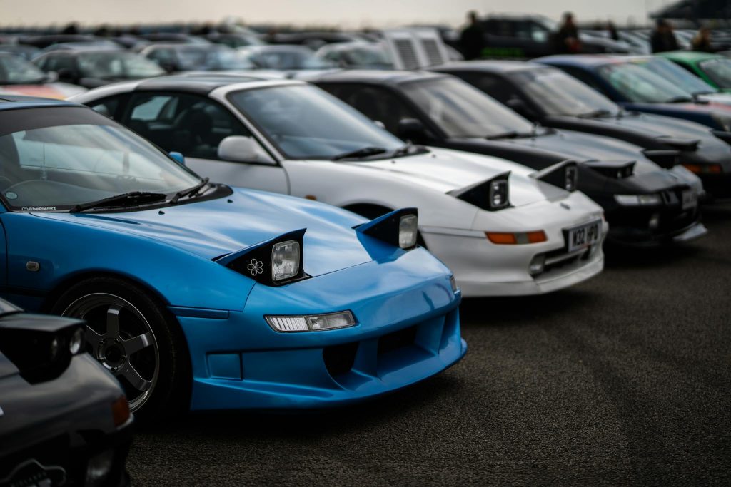 Toyota MR2 sports cars with popup headlights showcased at a car meet in England.